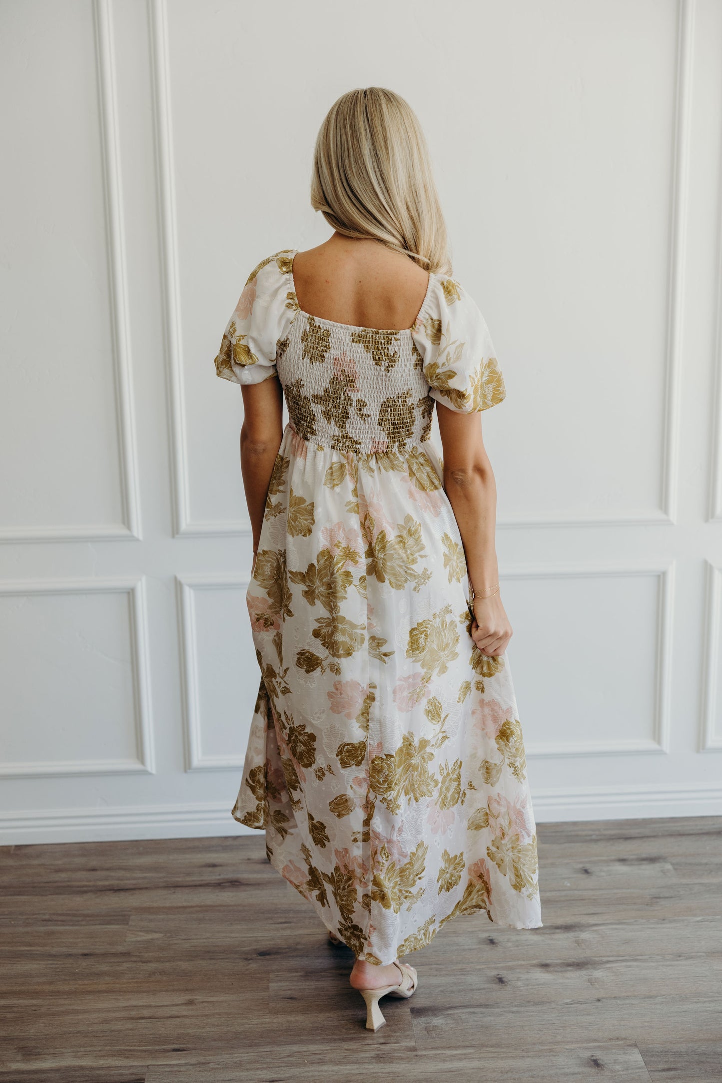Back view of pink and olive floral print dress with smocking in back.