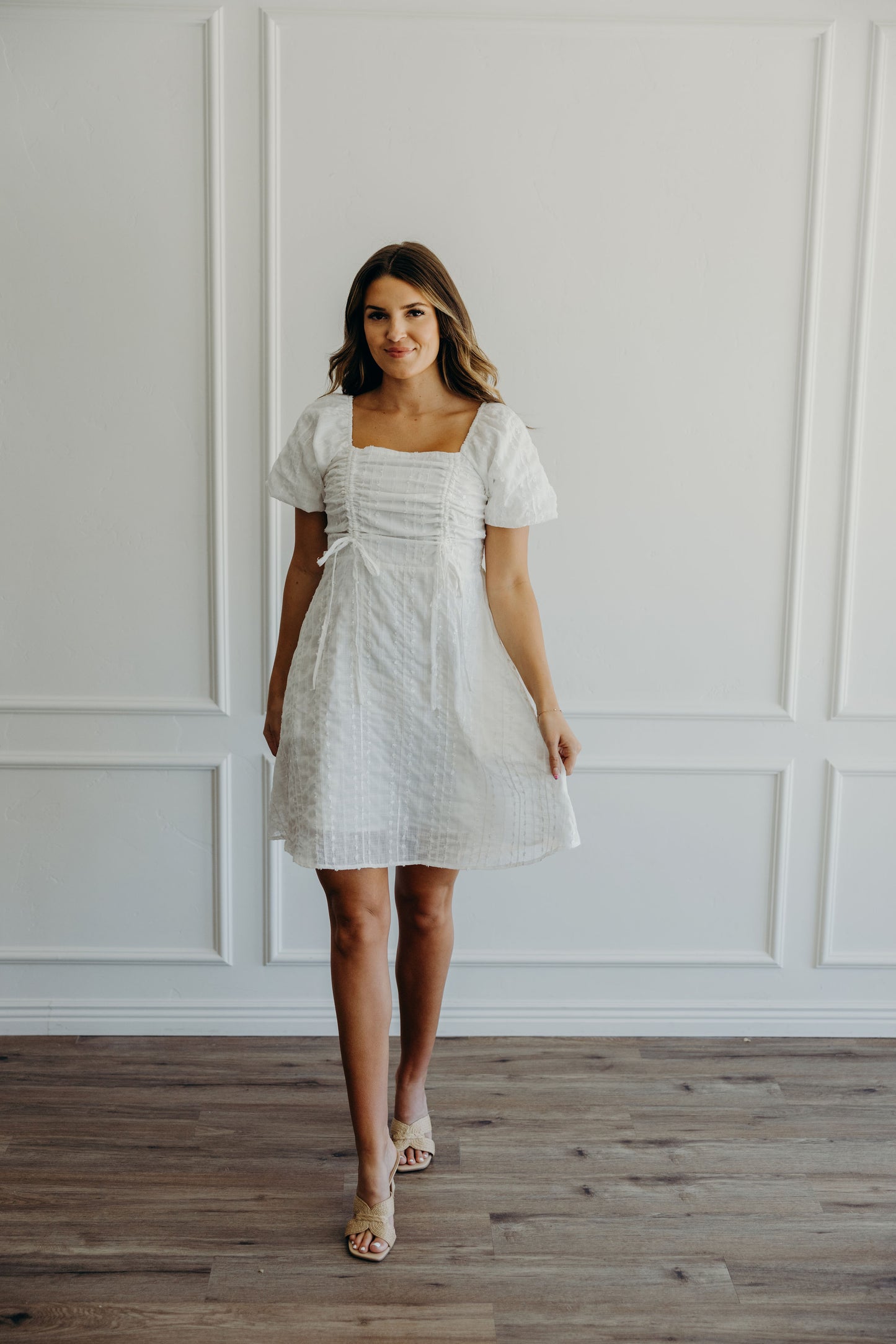 Short textured white dress with gathered tie detail on bust, short puff sleeves, and a line silhouette.