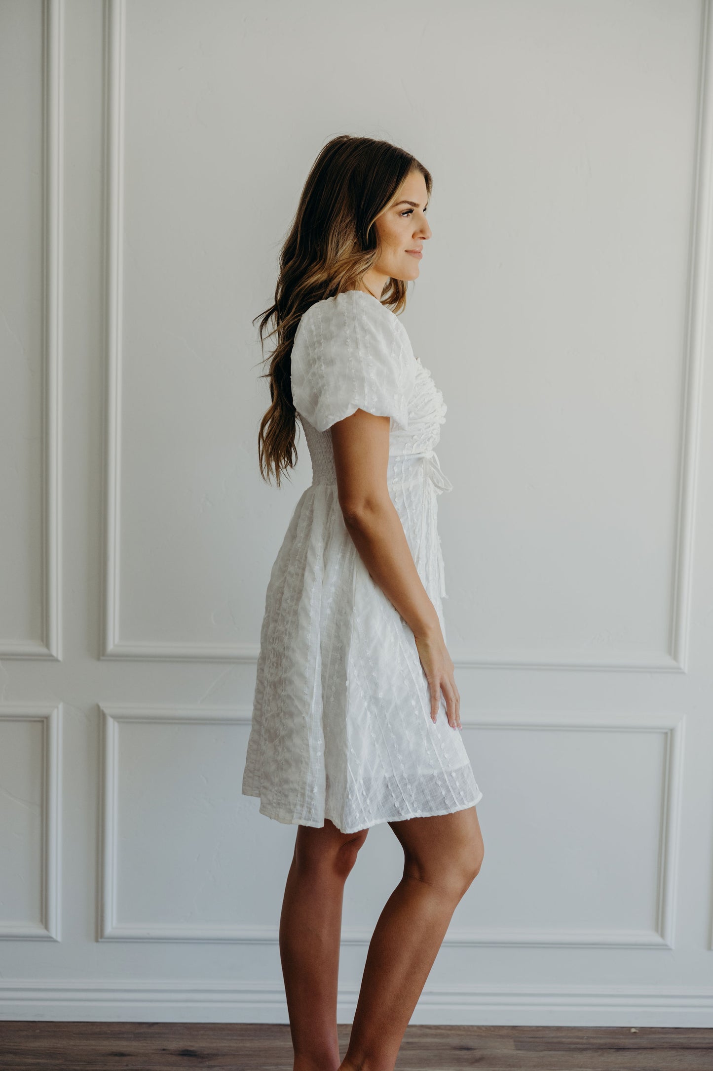 White dress with textured and gathered detail with knee length skirt and short sleeves.