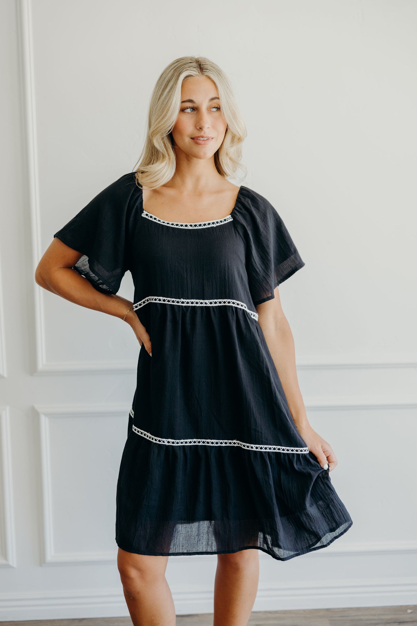 A line knee length dress with natural waist, square neckline, lace trim, and half length flutter sleeve.