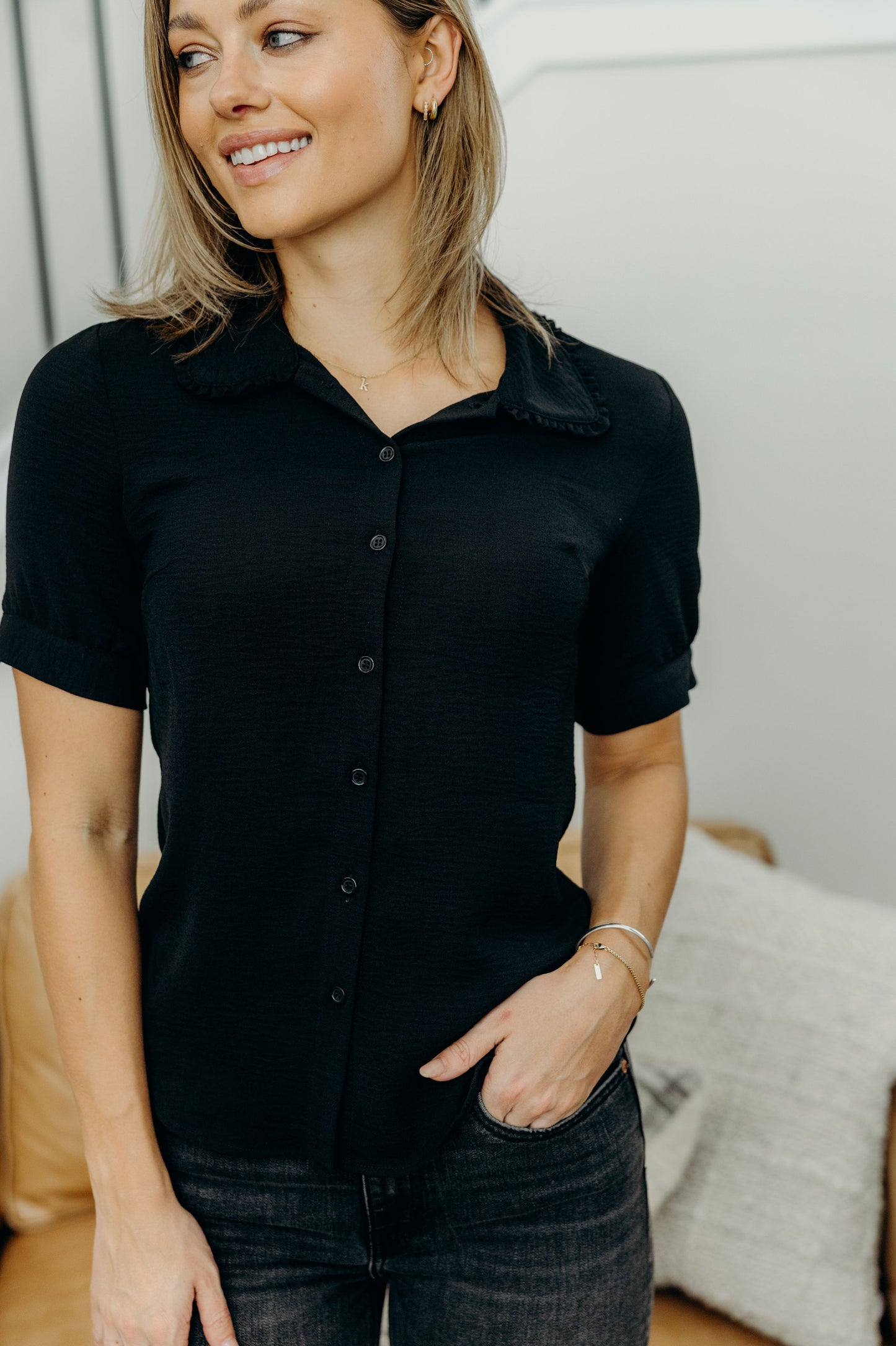 Black short sleeve button up top with ruffle detail on collar.
