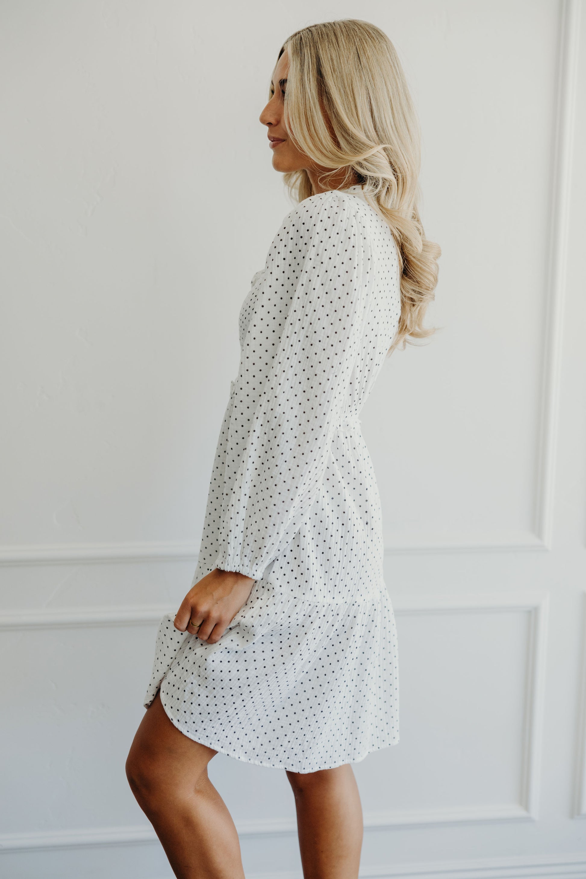Side view of knee length polka dot print long sleeve dress.