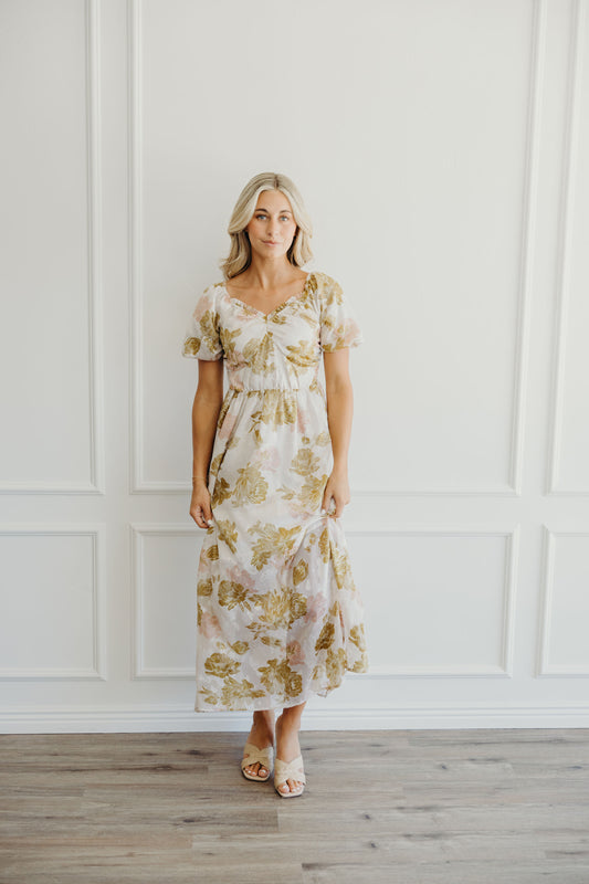 Midi length light pink and olive print dress with natural waistline and v neckline.