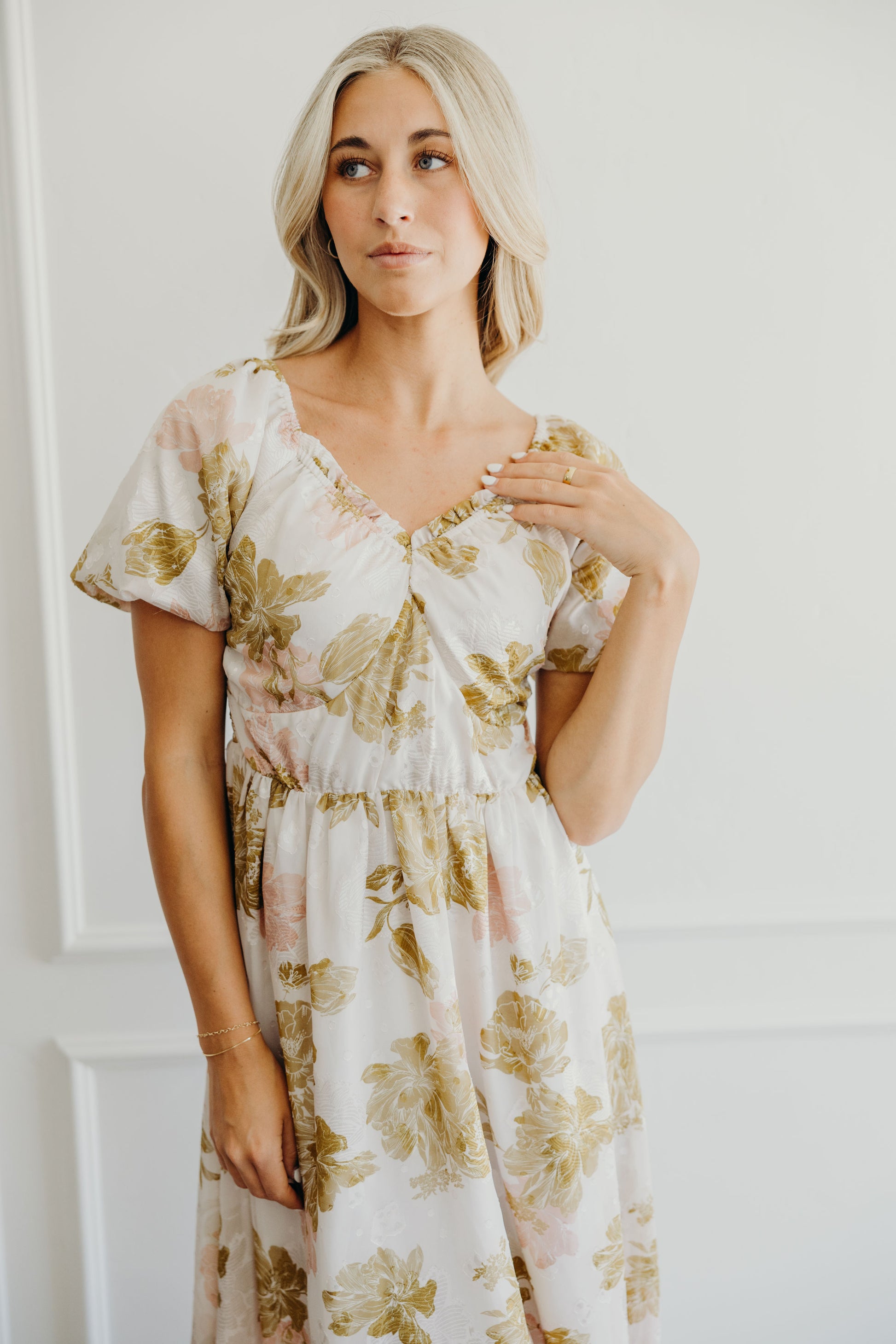 Detail shot of pink and olive print dress with sweetheart neckline and short sleeves.