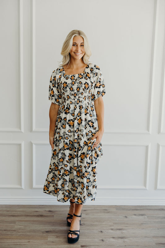 Midi length tiered dress with floral print, natural waistline, square neckline and puff sleeves.