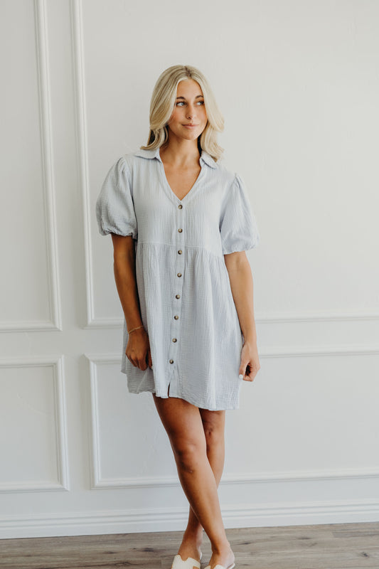 Short light blue dress with natural waistline, v neckline, puff sleeves, button down and collar details.
