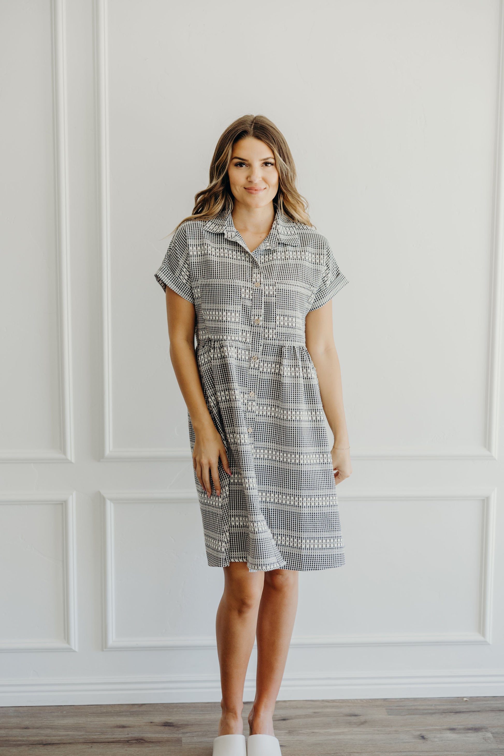 Knee length dress with fit and flare silhouette, pocket and button down detail on textured black and cream checkered dress.
