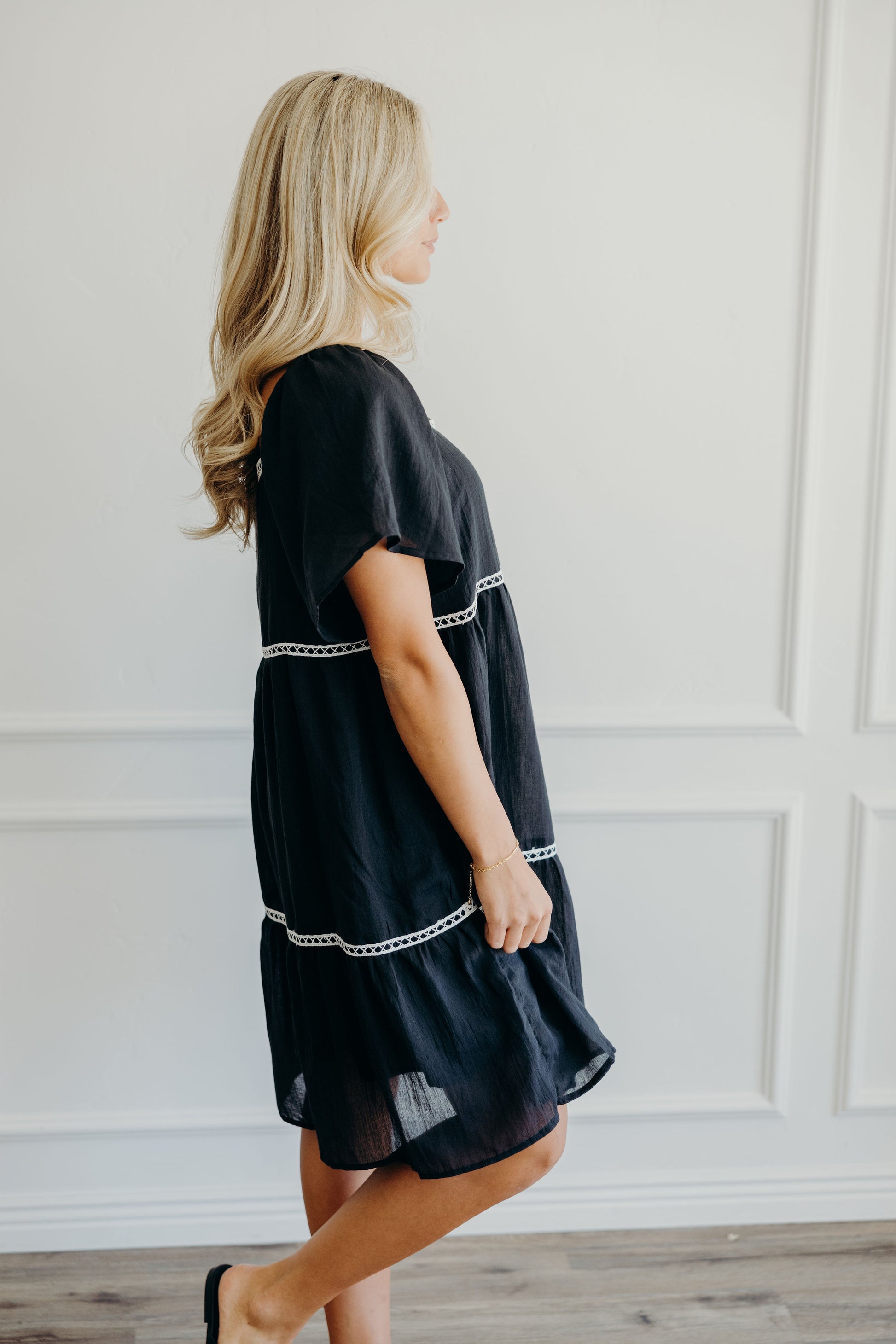 Black knee length dress with white lace detail and short sleeve.