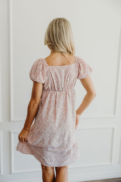 Back view of pink floral shift dress with elastic waist and puff sleeves.