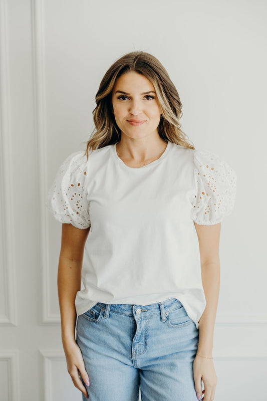 White shirt with round neckline with eyelet puff sleeves.
