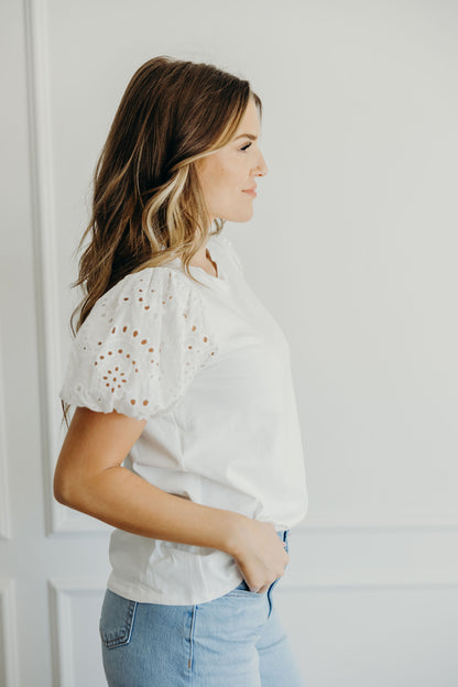 Side view of white short puff sleeve shirt with eyelet detail on sleeve.
