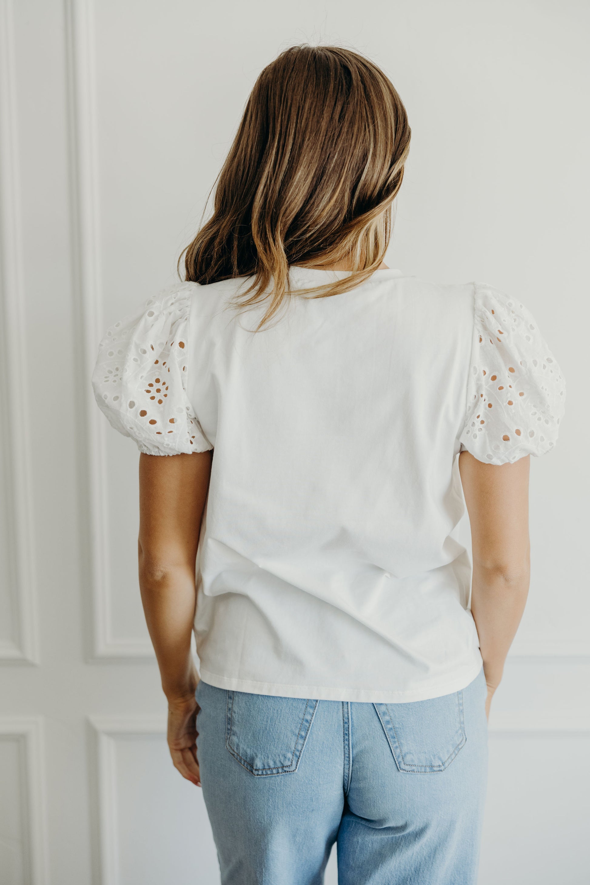 Back view of white eyelet shirt with puff sleeves.