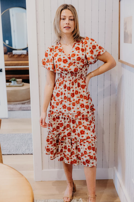 Midi length print dress with faux wrap bodice, short sleeves, smocked waist, and tiered skirt.