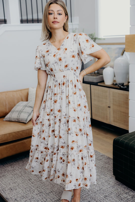 Maxi floral print dress with tiered skirt, smocked waist, v neckline, and short flutter sleeves.