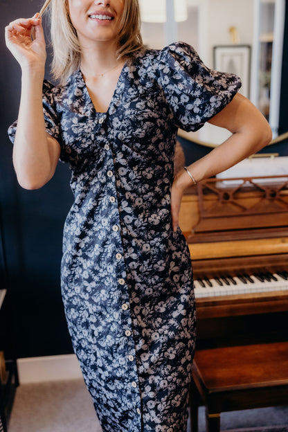 Button down floral print dress with v neckline and short puff sleeves with fitted silhouette.
