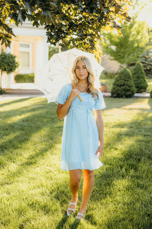 Short blue fit and flare silhouette dress with tie detail, square neckline, and short sleeves.