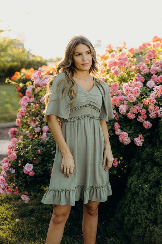 Short green dress with ruffle hem, ruffle detail at waist, sweetheart neckline and oversized sleeves.